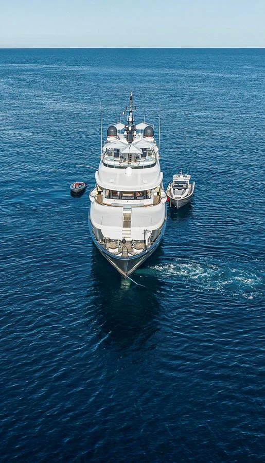 A luxurious yacht cruises on calm blue waters, accompanied by a tender. aboard LADY TRUDY Yacht for Sale