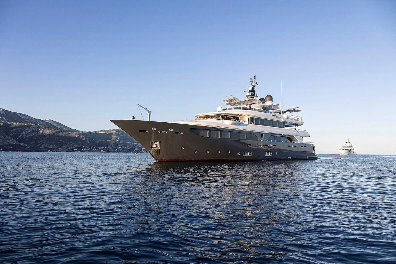 A luxurious yacht glides gracefully on calm waters with a scenic mountainous backdrop. aboard LADY TRUDY Yacht for Sale