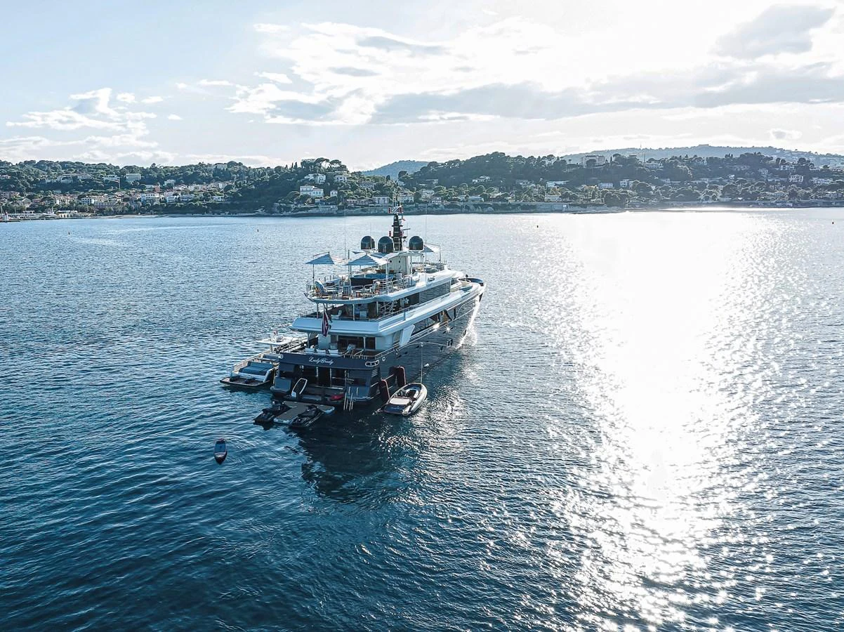 A luxurious yacht is anchored in a serene bay with a picturesque coastal backdrop. aboard LADY TRUDY Yacht for Sale