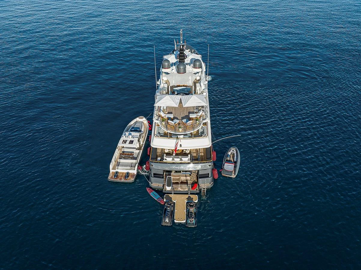 The yacht is anchored in calm waters, showcasing its aft deck and accompanying tenders. aboard LADY TRUDY Yacht for Sale