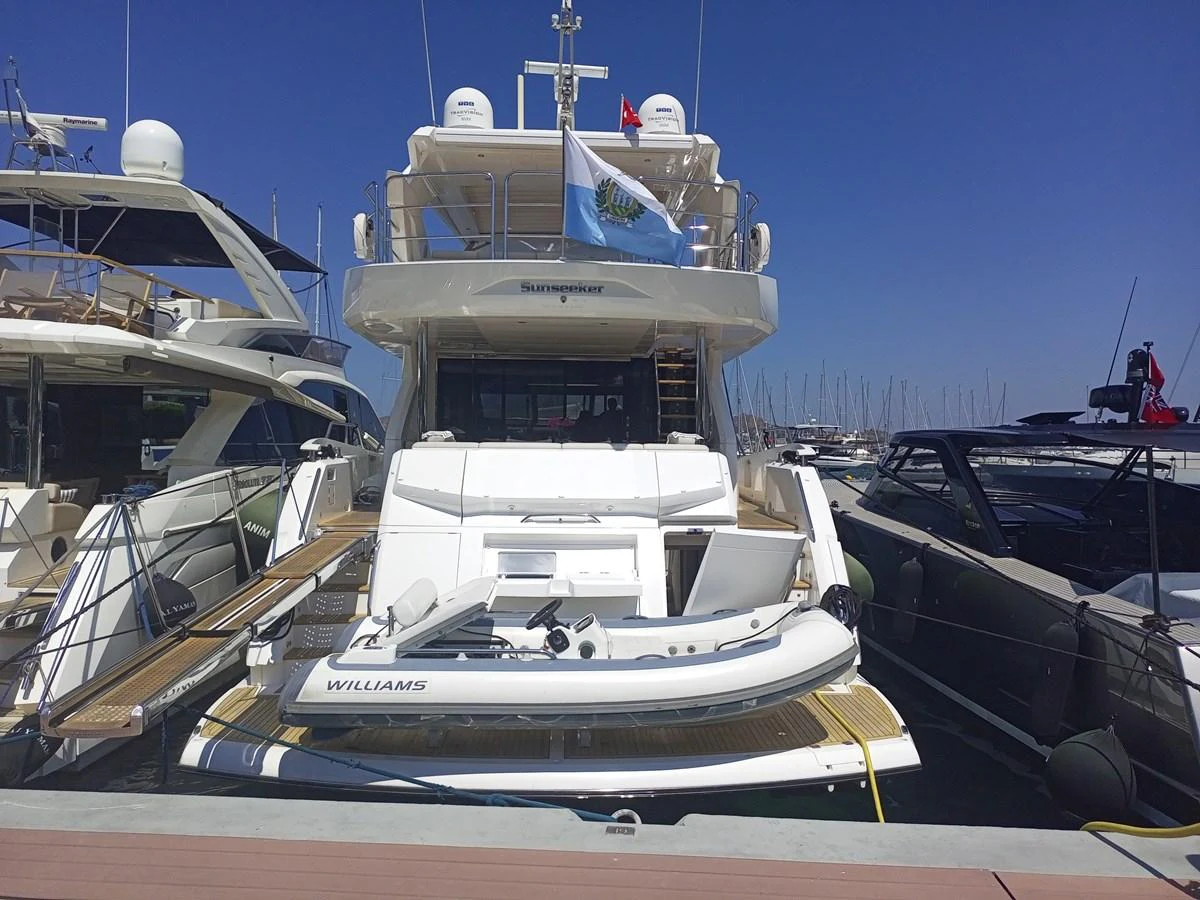 A yacht tender is secured at the stern of a luxurious yacht docked at a marina. aboard ANM Yacht for Sale