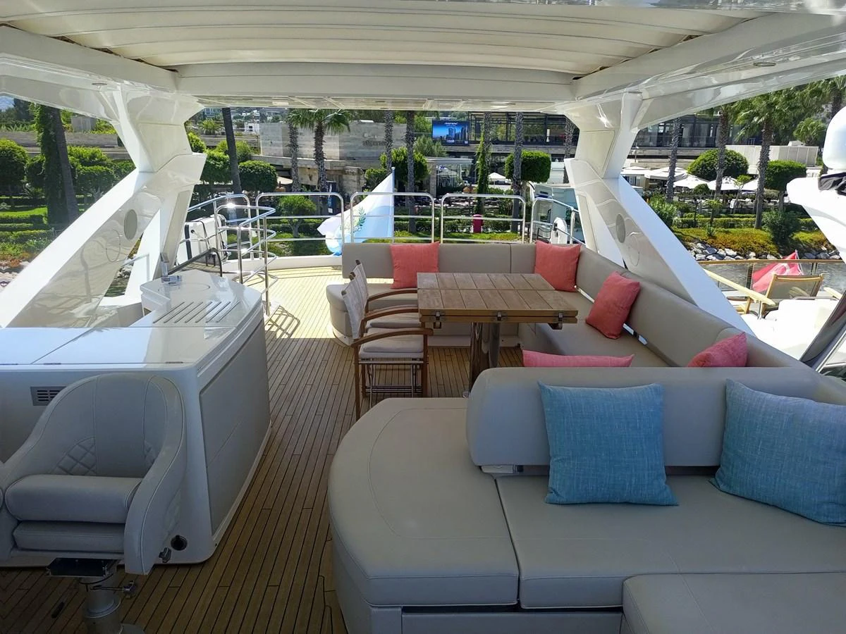The flybridge offers a spacious and comfortable seating area with a dining table and plush cushions. aboard ANM Yacht for Sale