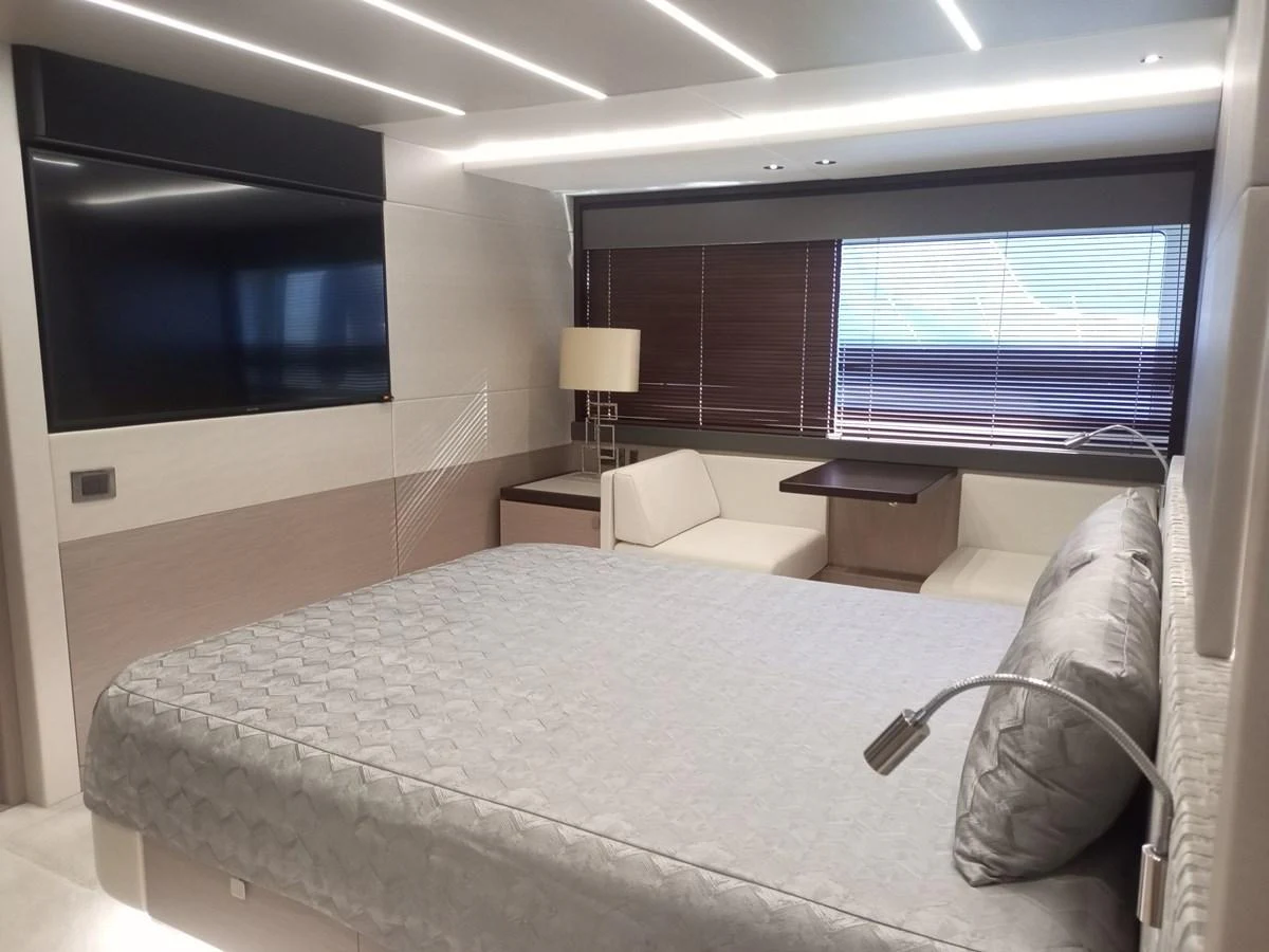 The stateroom features a comfortable bed, modern lighting, and a cozy seating area by the window. aboard ANM Yacht for Sale