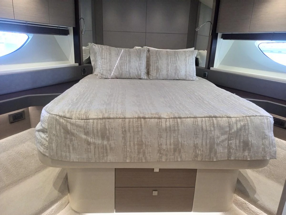 The stateroom features a luxurious bed with modern decor and ample natural light from the side windows. aboard ANM Yacht for Sale