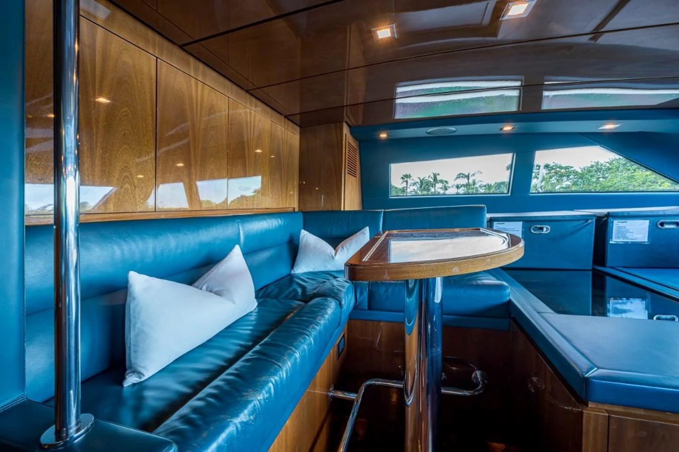 The yacht's interior features a cozy seating area with plush blue leather cushions and a polished wooden table. aboard ALEGHI Yacht for Sale