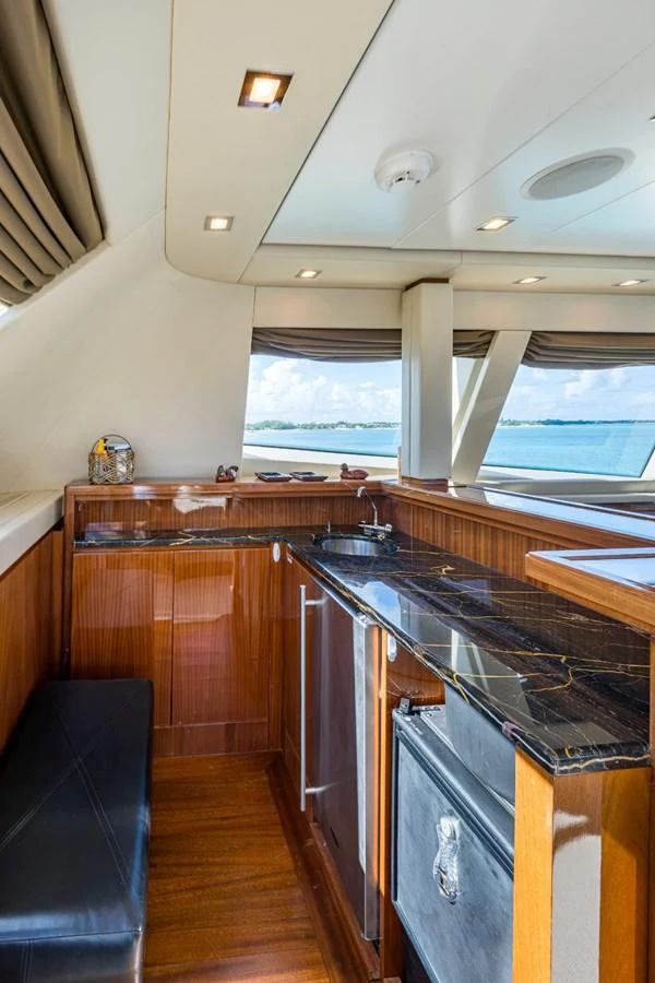 The yacht's galley features sleek wood cabinetry and a black marble countertop with a view of the sea through large windows. aboard ALEGHI Yacht for Sale