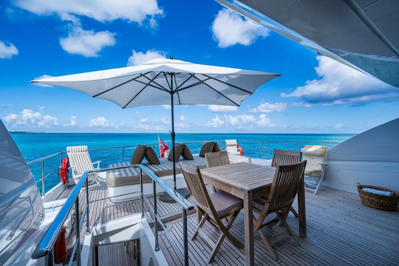 The aft deck features a spacious dining area with a large umbrella providing shade, perfect for enjoying meals with a stunning ocean view. aboard ALEGHI Yacht for Sale
