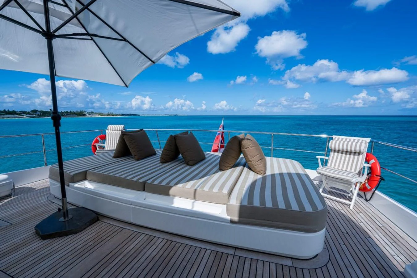The sundeck offers a luxurious lounging area with comfortable sunbeds and a large umbrella, perfect for relaxation. aboard ALEGHI Yacht for Sale