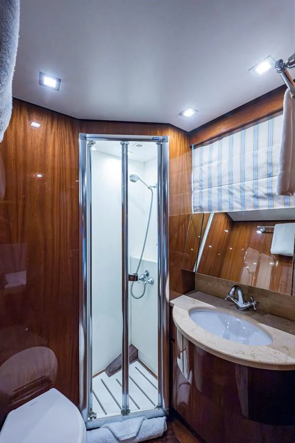 The yacht's bathroom features a sleek shower, elegant wood paneling, and a modern sink area. aboard ALEGHI Yacht for Sale