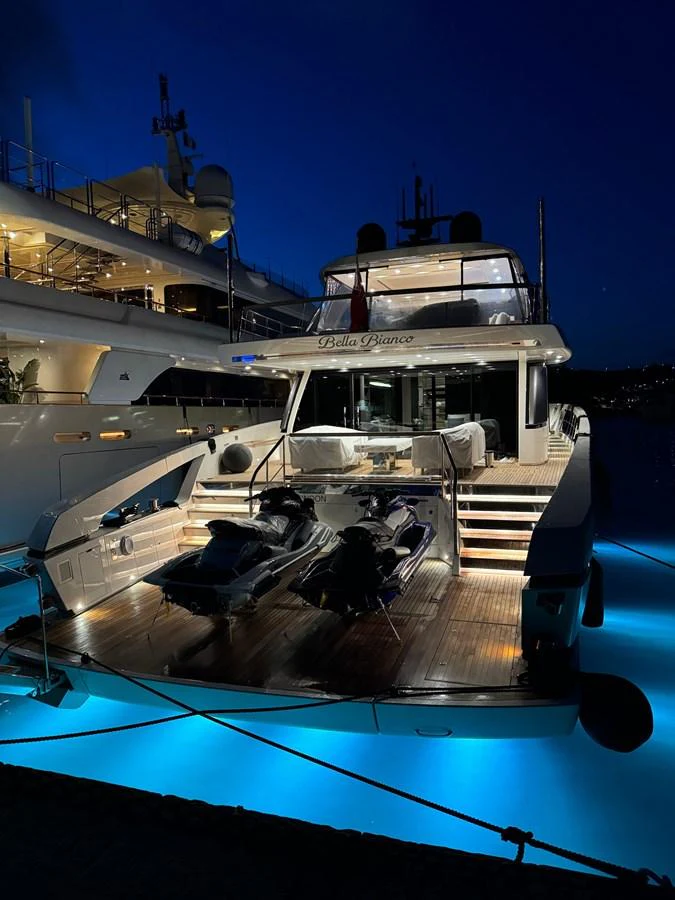 The yacht's aft deck is beautifully illuminated at night, showcasing a luxurious and inviting space. aboard BELLA B Yacht for Sale
