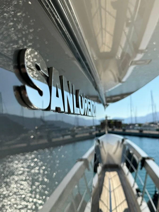 A close-up view of the yacht's nameplate reflecting the serene marina waters. aboard BELLA B Yacht for Sale