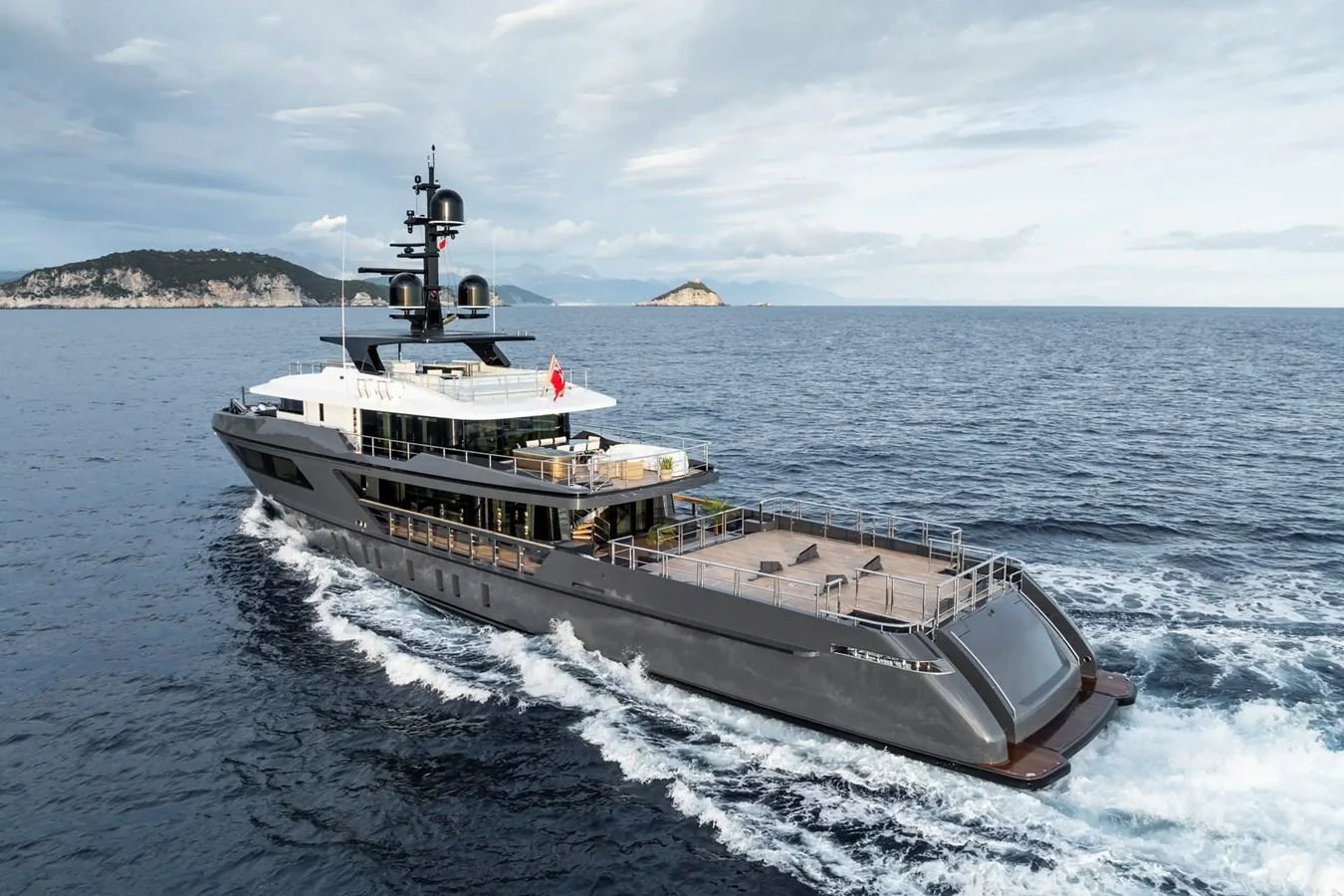 A sleek and modern yacht cruises through open waters with scenic islands in the background. aboard BIG SHARK Yacht for Sale