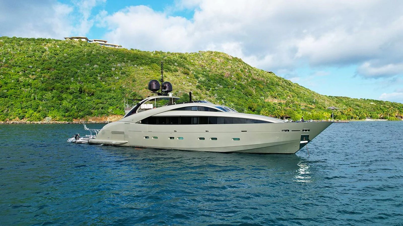 A sleek, modern yacht is anchored in a serene bay with lush green hills in the background. aboard YCM 120 Yacht for Sale