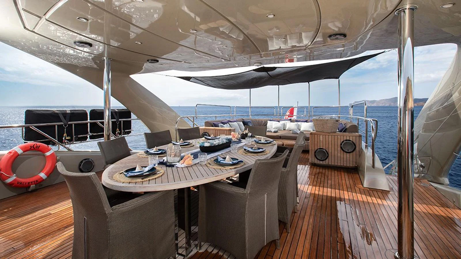 The aft deck features an elegant dining area with a large table and comfortable seating, perfect for alfresco meals with a stunning ocean view. aboard YCM 120 Yacht for Sale