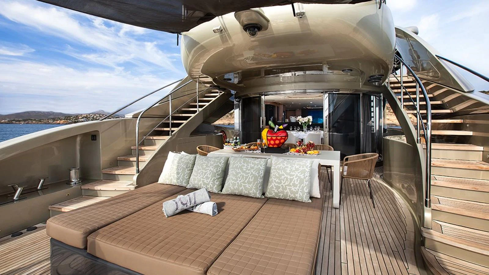 The aft deck features a luxurious lounging area with a dining setup, perfect for alfresco meals and relaxation. aboard YCM 120 Yacht for Sale