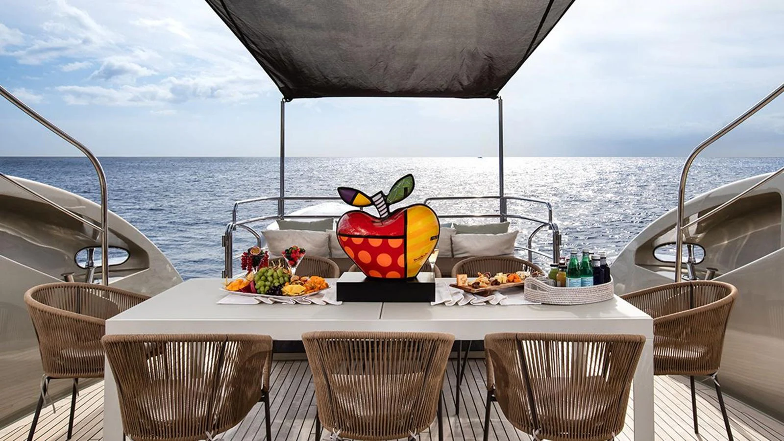 The aft deck features a stylish dining area with a modern table set for a meal, complemented by a stunning ocean view. aboard YCM 120 Yacht for Sale
