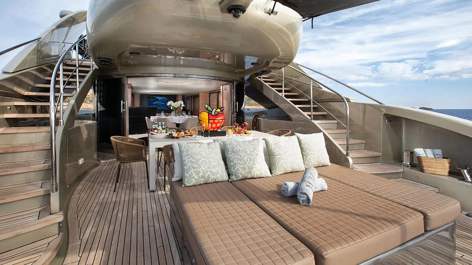 The aft deck features a comfortable lounging area with plush cushions and a dining setup for a relaxing experience. aboard YCM 120 Yacht for Sale
