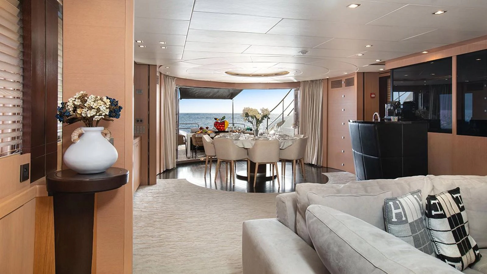 The yacht's salon features elegant decor with a spacious seating area and a dining table overlooking the sea. aboard YCM 120 Yacht for Sale