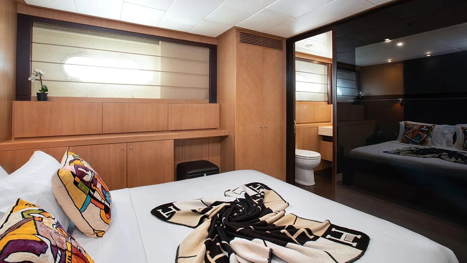 A luxurious stateroom featuring a comfortable bed, elegant wood paneling, and a private ensuite bathroom. aboard YCM 120 Yacht for Sale