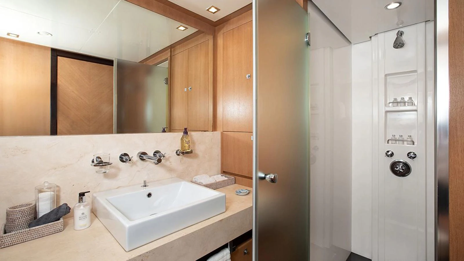 The yacht's bathroom features a modern sink, wooden cabinetry, and a glass-enclosed shower. aboard YCM 120 Yacht for Sale