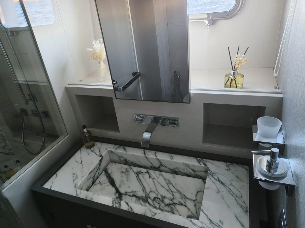 The yacht's bathroom features a sleek design with a marble sink and modern fixtures. aboard HONEY Yacht for Sale