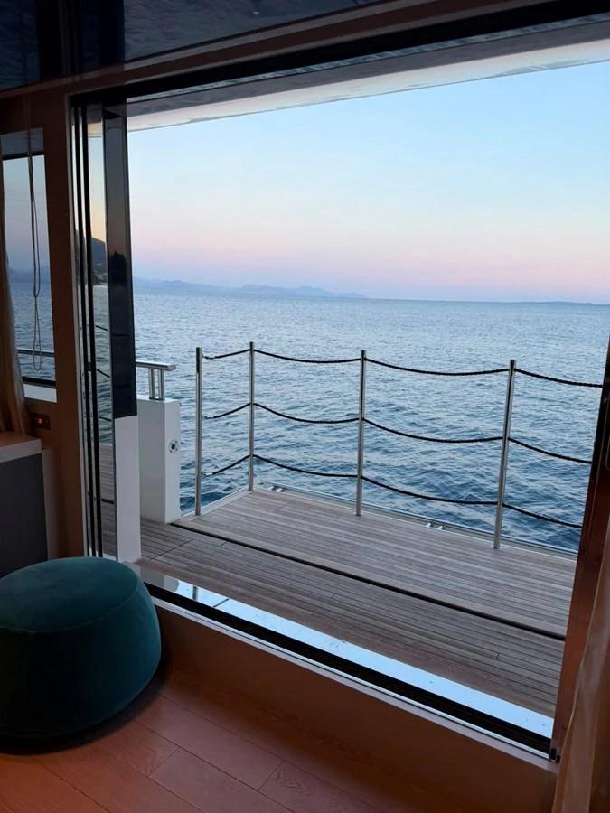 A serene view of the ocean from the yacht's interior, framed by large windows and a cozy seating area. aboard HONEY Yacht for Sale