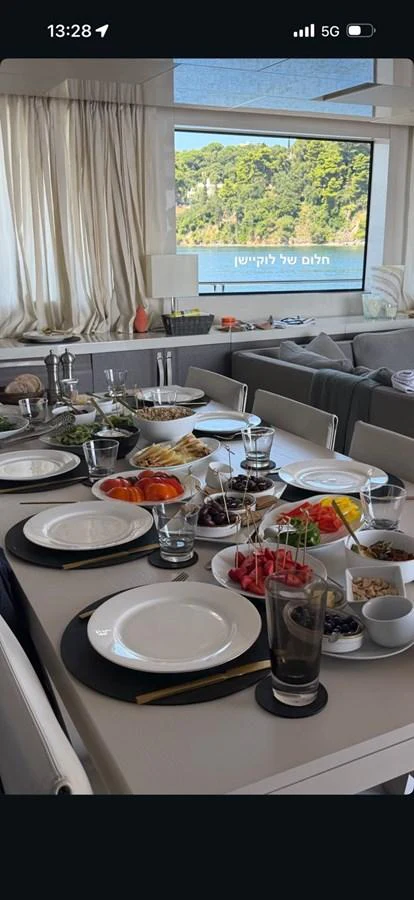 The interior dining area is elegantly set with a variety of dishes and a scenic view through the window. aboard HONEY Yacht for Sale