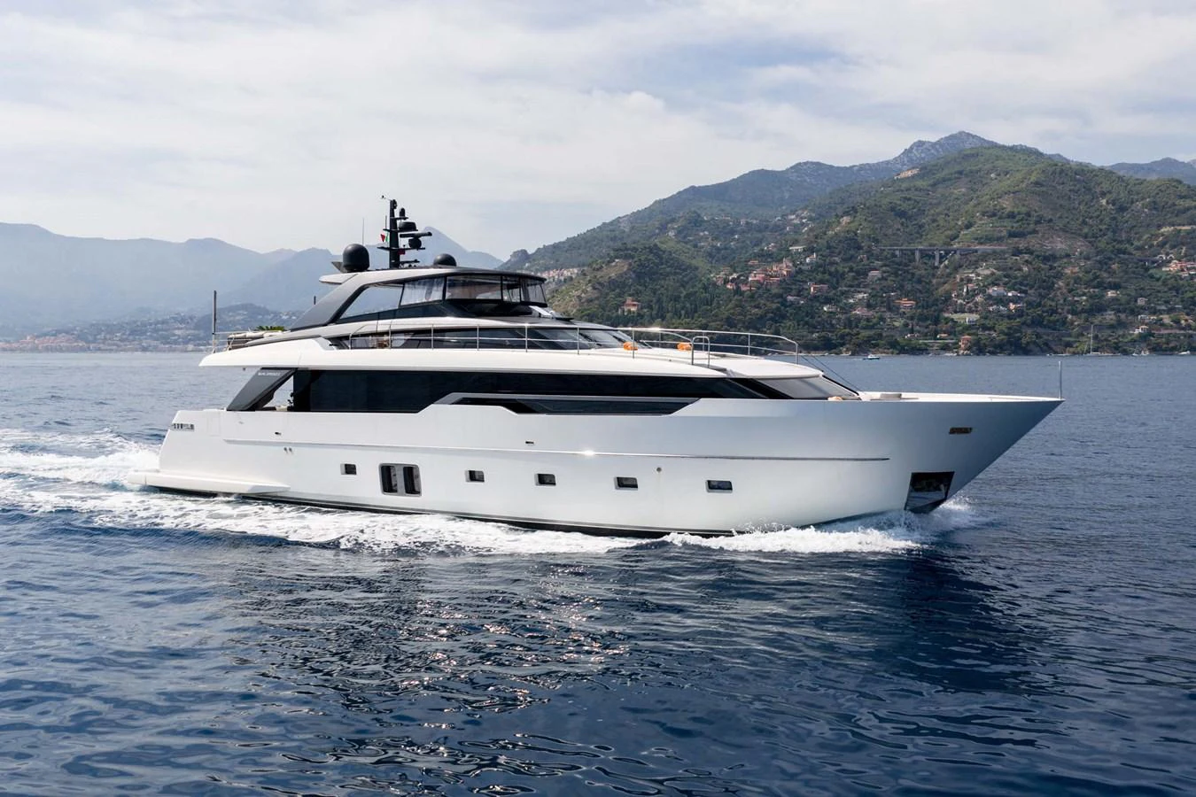 A sleek, modern yacht cruising on calm waters with scenic hills in the background. aboard JACKI 8 Yacht for Sale