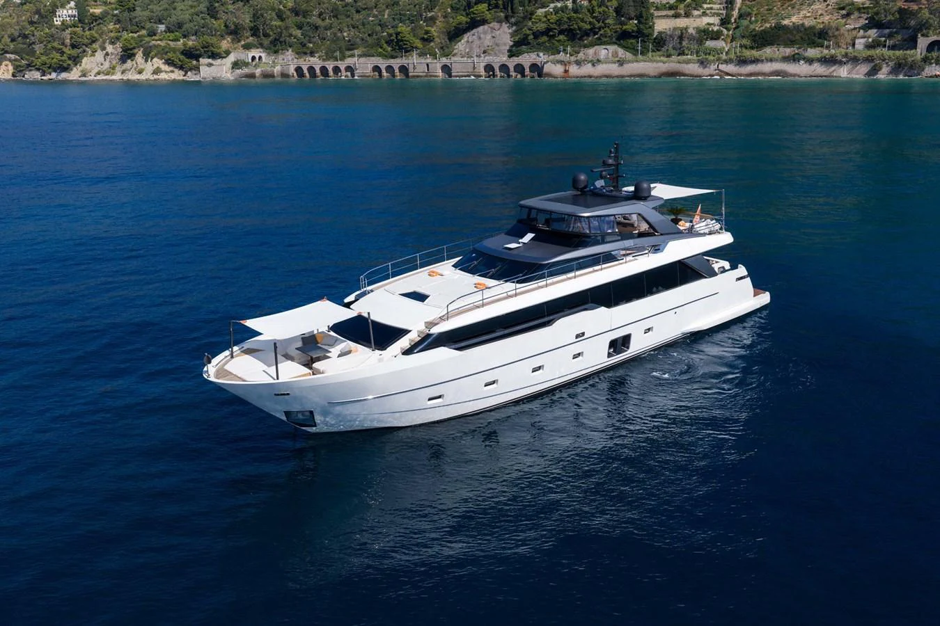 A sleek yacht cruises through calm waters near a scenic coastline. aboard JACKI 8 Yacht for Sale