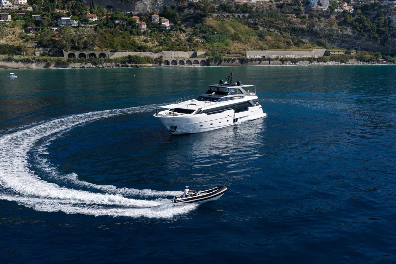 A luxurious yacht cruises through clear blue waters, accompanied by a sleek tender. aboard JACKI 8 Yacht for Sale