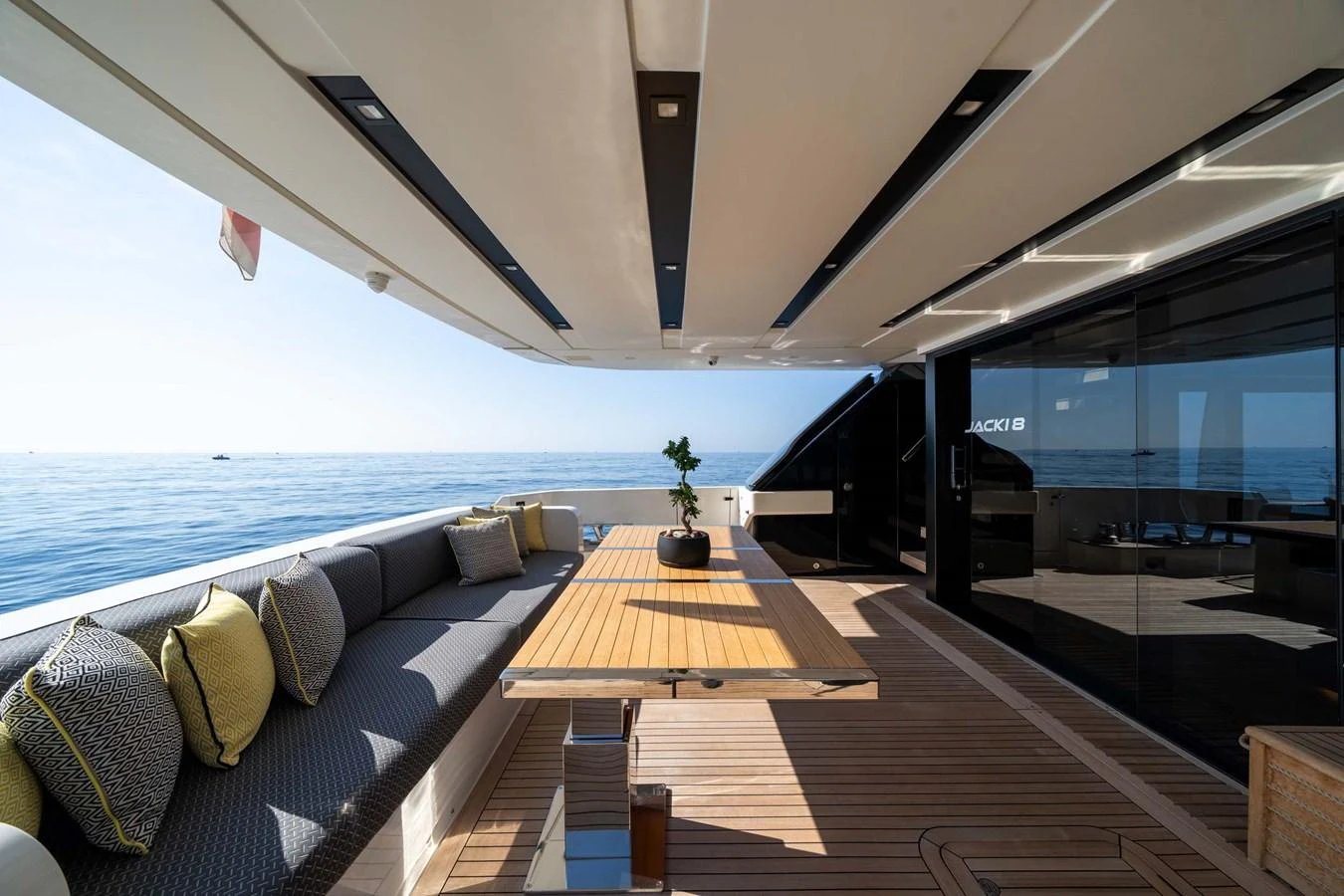 The aft deck features a spacious seating area with a wooden table and comfortable cushions, perfect for relaxing and enjoying the ocean view. aboard JACKI 8 Yacht for Sale
