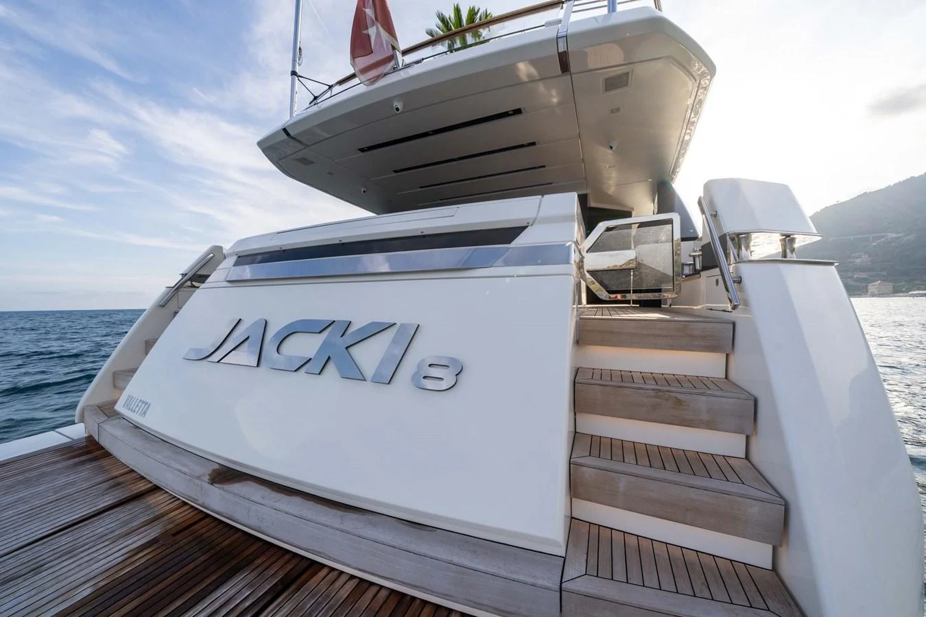 The yacht's aft deck features elegant wooden steps leading up to the main deck, with sleek design elements and a polished finish. aboard JACKI 8 Yacht for Sale