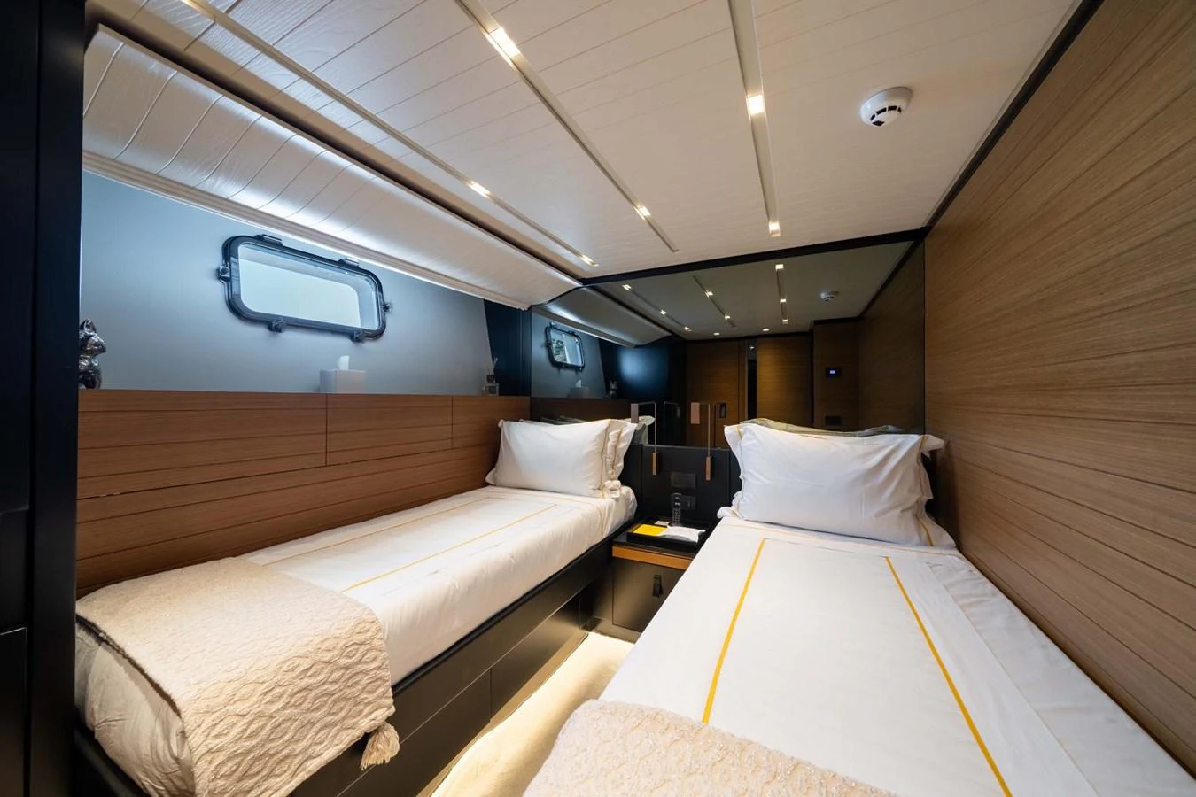 The twin stateroom features two comfortable single beds with elegant bedding and modern lighting. aboard JACKI 8 Yacht for Sale