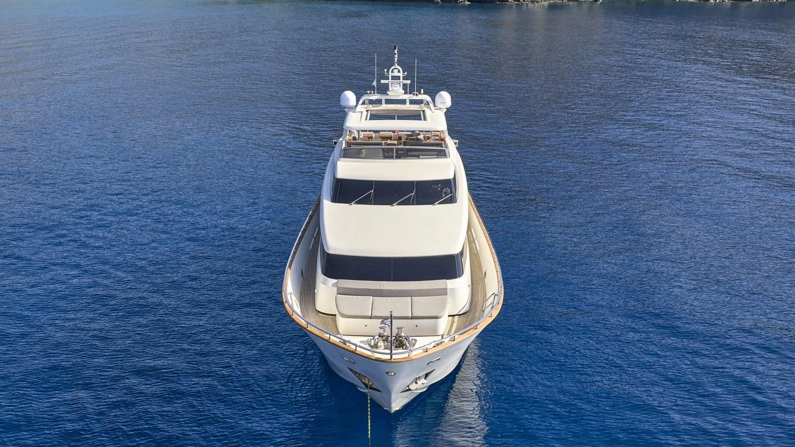 A luxurious yacht is gracefully positioned on the serene blue waters, showcasing its elegant design from a head-on view. aboard OASIS Yacht for Sale
