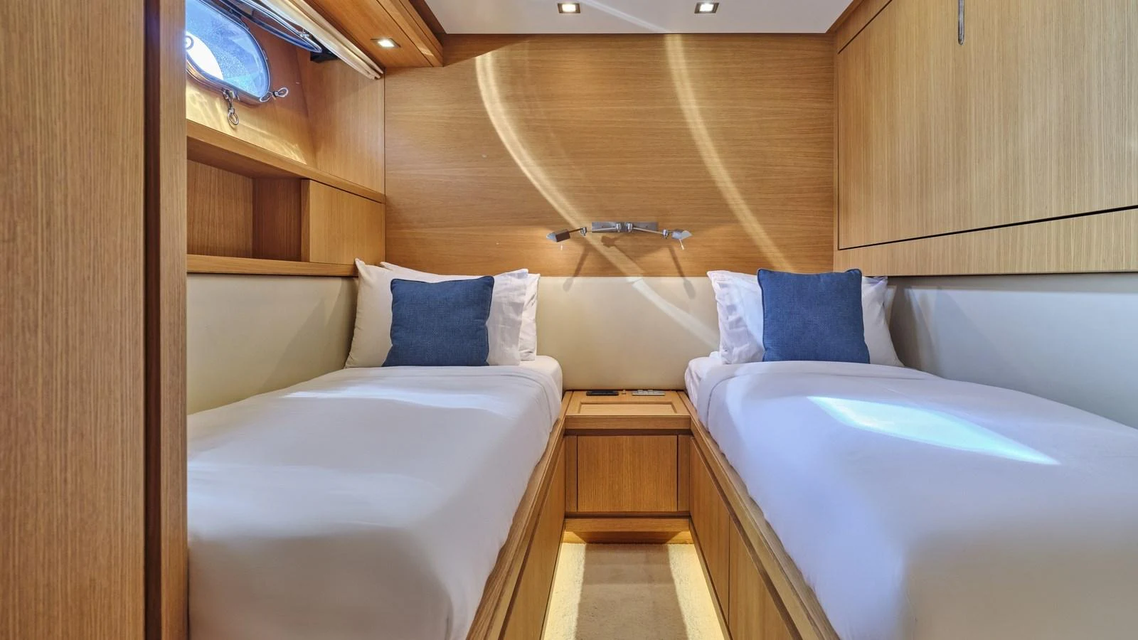 The twin stateroom features two comfortable single beds with plush pillows and warm wooden finishes. aboard OASIS Yacht for Sale