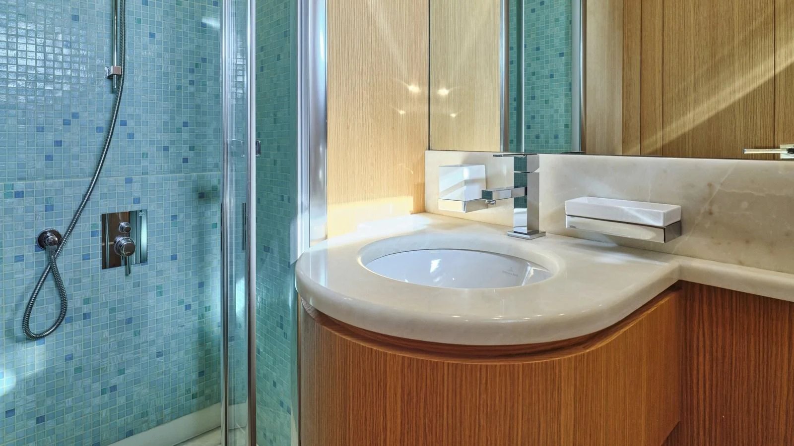 The yacht's bathroom features a modern design with a sleek sink and a glass-enclosed shower. aboard OASIS Yacht for Sale