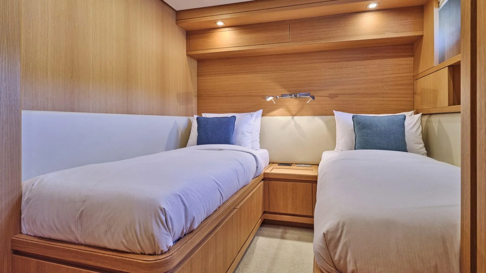 The twin stateroom features two comfortable single beds with plush pillows and modern wooden finishes. aboard OASIS Yacht for Sale