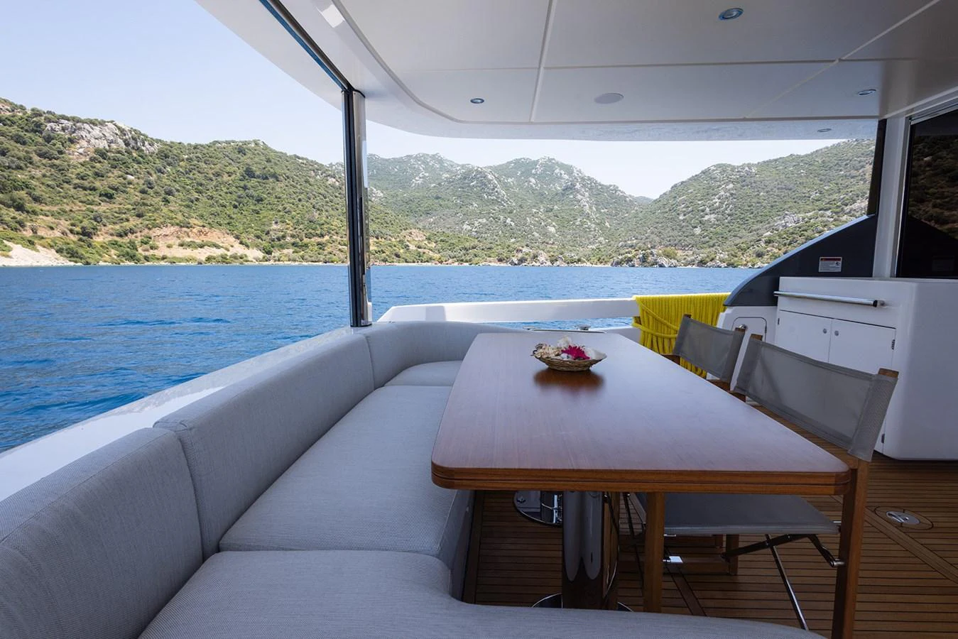 The aft deck offers a comfortable seating area with a dining table, perfect for enjoying meals with a scenic view. aboard MILES Yacht for Sale