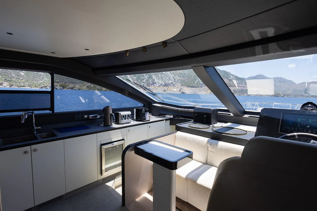 The yacht's galley features modern appliances and a comfortable seating area with stunning views through large windows. aboard MILES Yacht for Sale