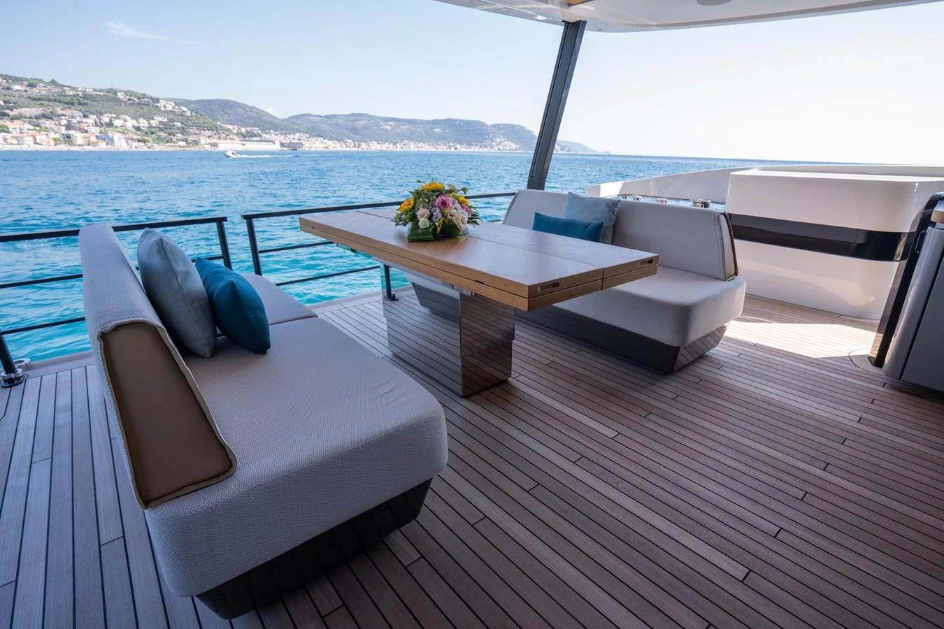 The aft deck features a stylish seating area with a wooden table and plush cushions, perfect for enjoying the ocean views. aboard COME TOGETHER Yacht for Sale