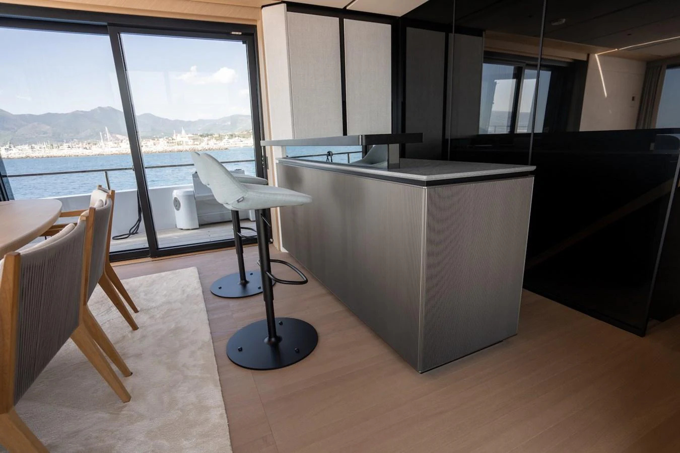 The salon features a modern dining area with a view of the sea through large windows. aboard COME TOGETHER Yacht for Sale