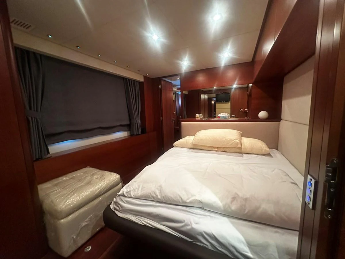 The stateroom features a comfortable bed with luxurious bedding and warm wood finishes. aboard GALLEN Yacht for Sale