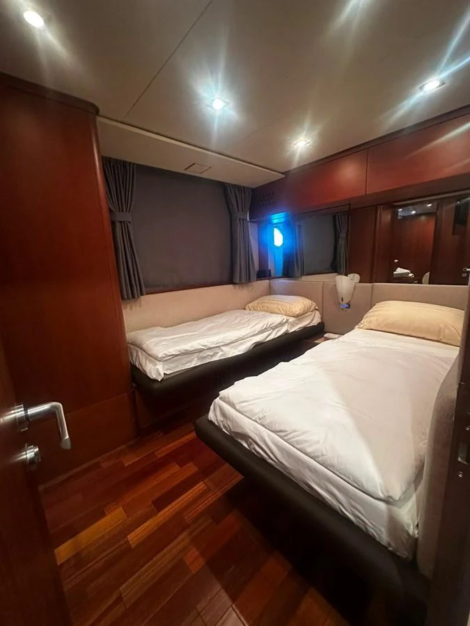 A cozy twin stateroom with warm wood finishes and soft lighting. aboard GALLEN Yacht for Sale