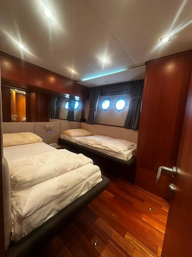 The guest stateroom features twin beds, rich wood paneling, and soft lighting for a cozy retreat. aboard GALLEN Yacht for Sale