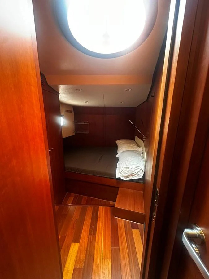 A cozy yacht cabin with warm wooden finishes and a circular skylight. aboard GALLEN Yacht for Sale