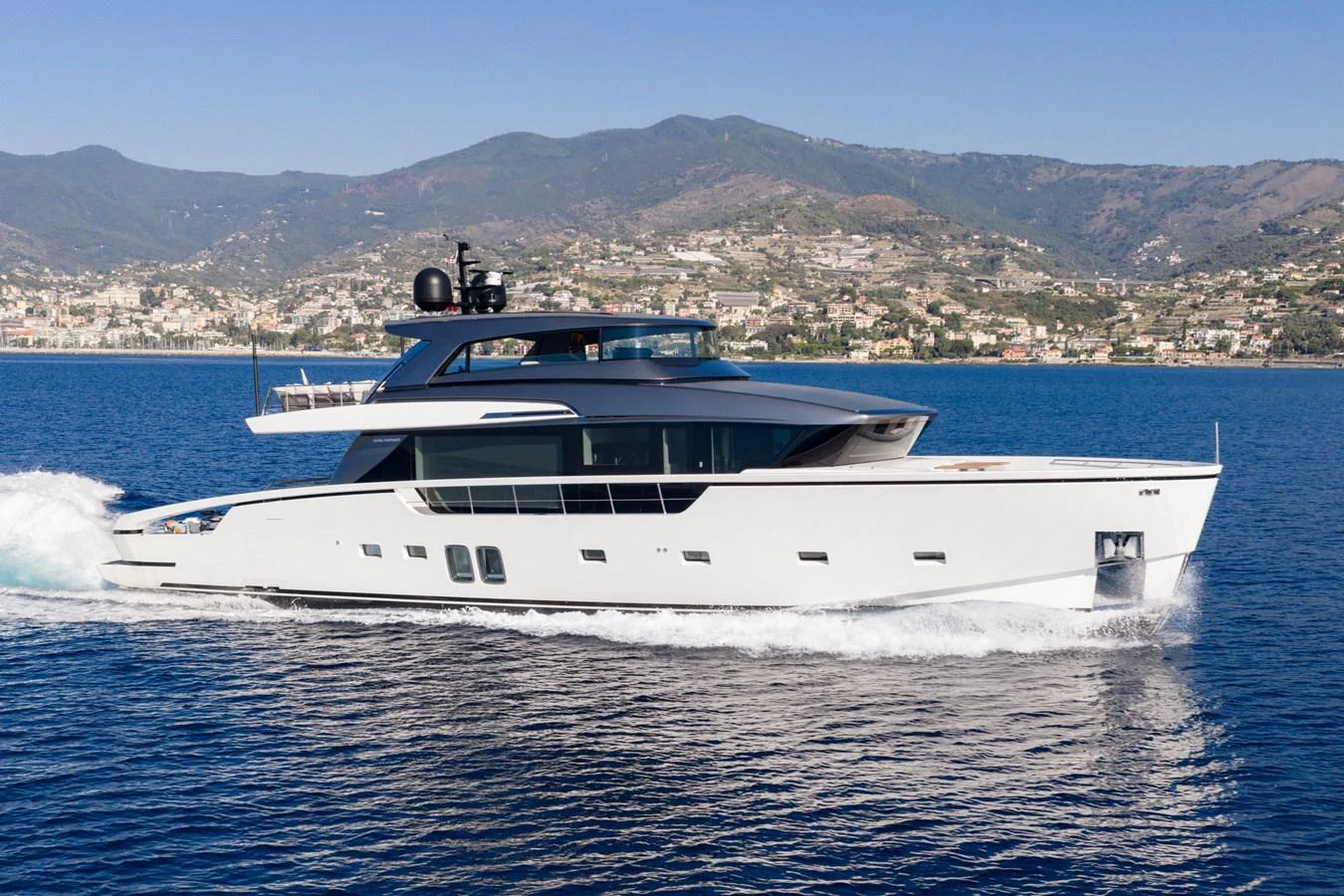 A sleek and modern yacht cruises gracefully on calm waters with a scenic coastal backdrop. aboard JUNIOR Yacht for Sale