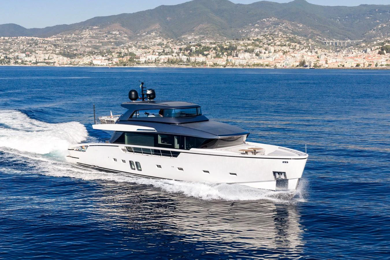 A sleek and modern yacht cruising on calm waters with a scenic coastal backdrop. aboard JUNIOR Yacht for Sale