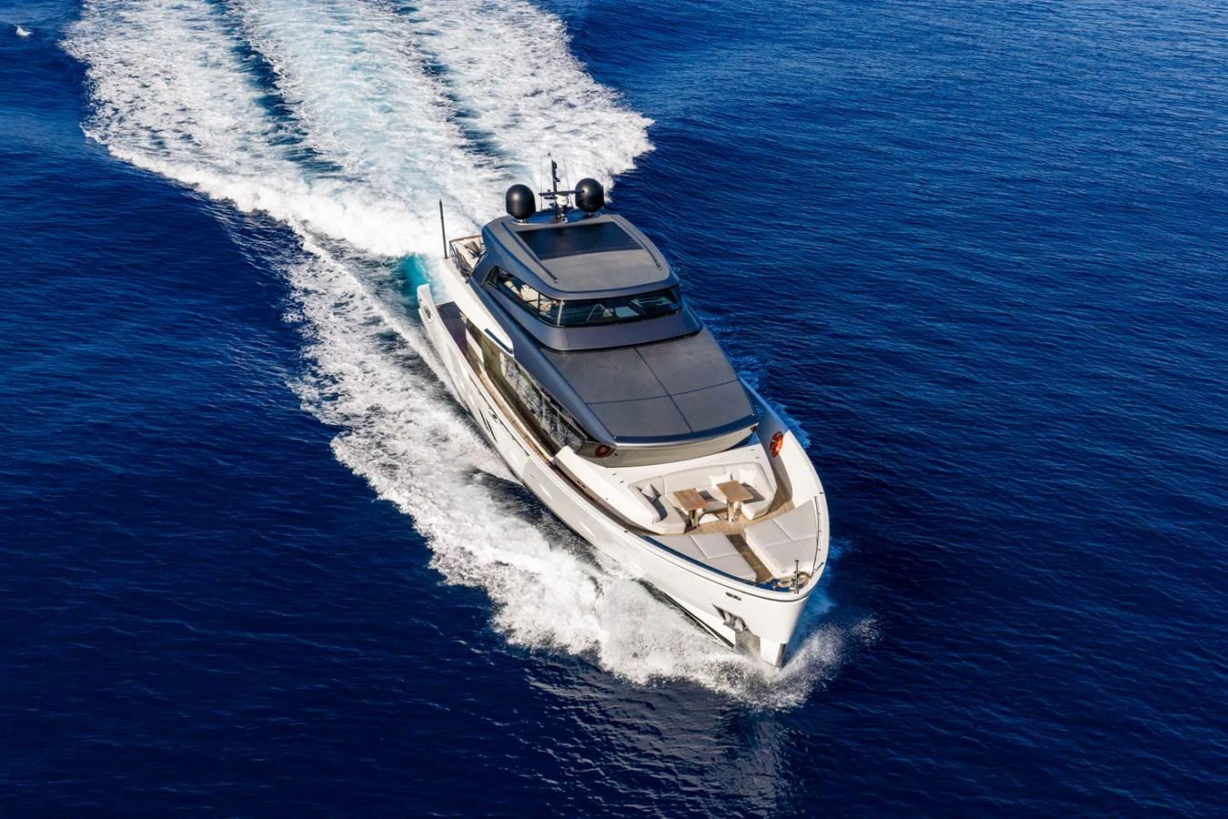 A sleek yacht cruises swiftly through the open sea, leaving a trail of white wake behind. aboard JUNIOR Yacht for Sale