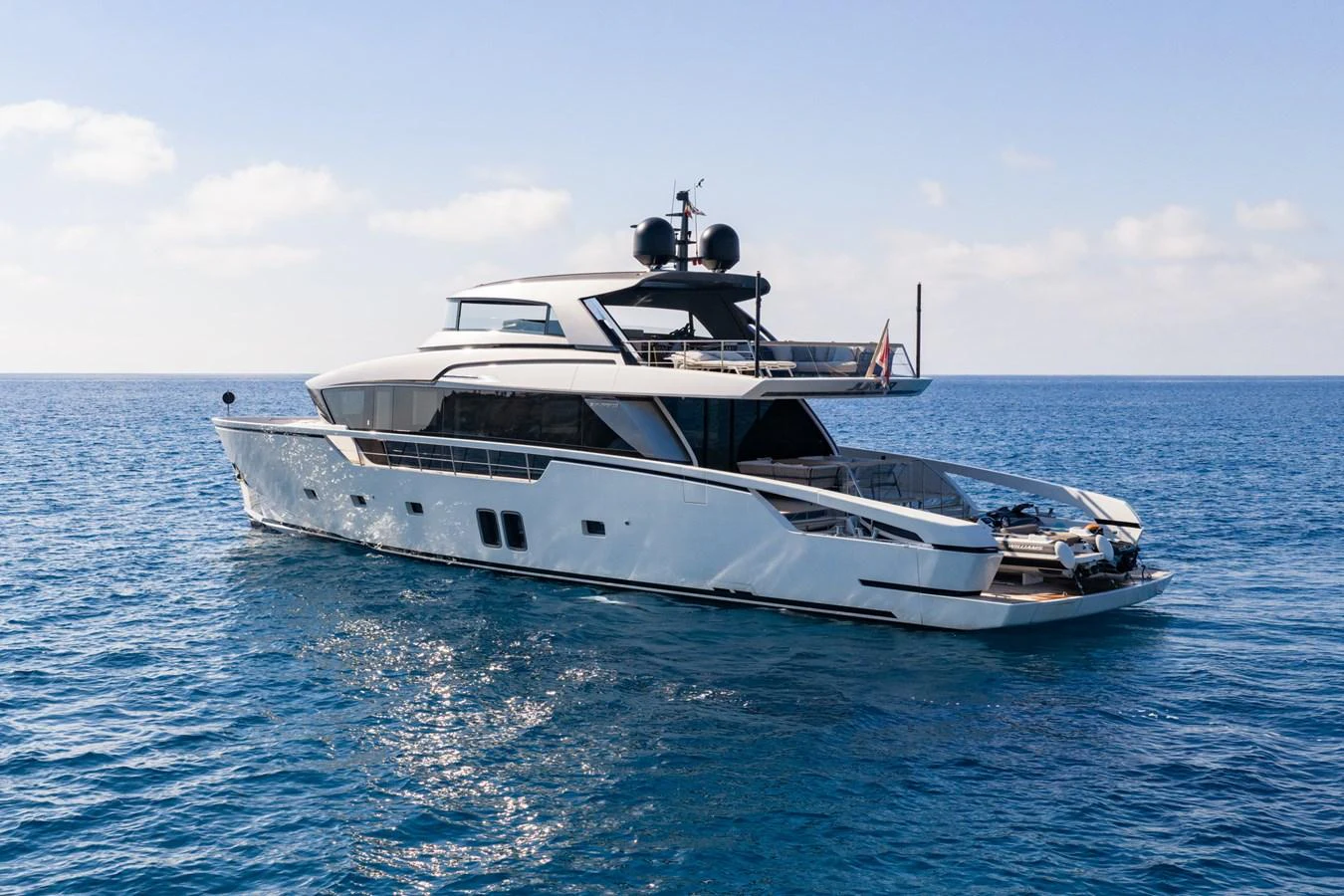 A sleek and modern yacht cruising on calm blue waters under a clear sky. aboard JUNIOR Yacht for Sale