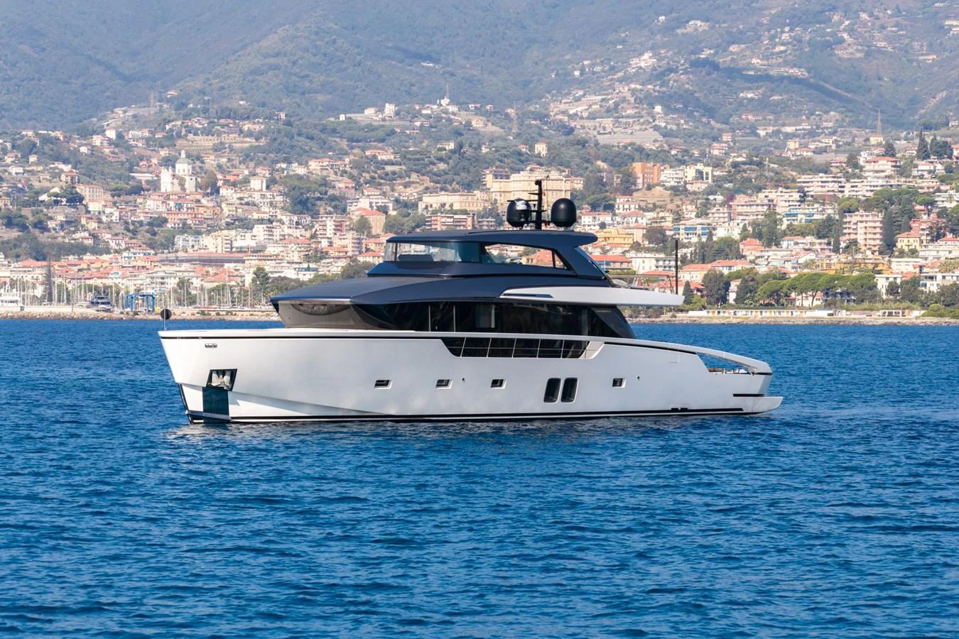 A sleek and modern yacht cruises gracefully on calm waters with a scenic coastal backdrop. aboard JUNIOR Yacht for Sale